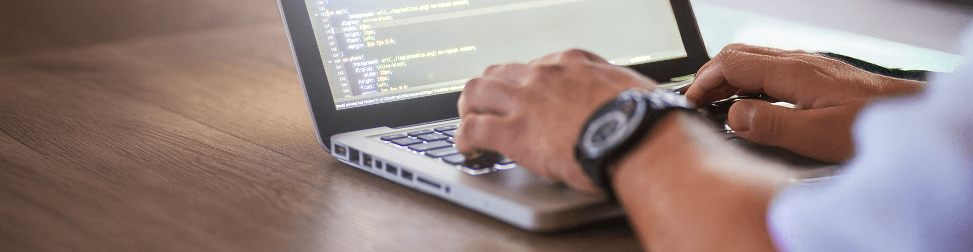 Hände tippen Code auf Laptop.