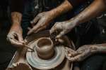 four hands shaping pottery on the wheel Shot