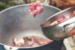 Putting lamb cuts into the stew Shot