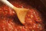 stirring marinara sauce in a pot with a wooden spoon Shot