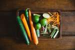 wooden tray with carrots, limes, and cucumber for spring rolls Shot