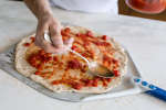 Chef spreading tomato sauce on focaccia pizza | Classpop