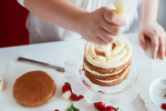 Chef piping vanilla icing onto tiered cake | Classpop Shot