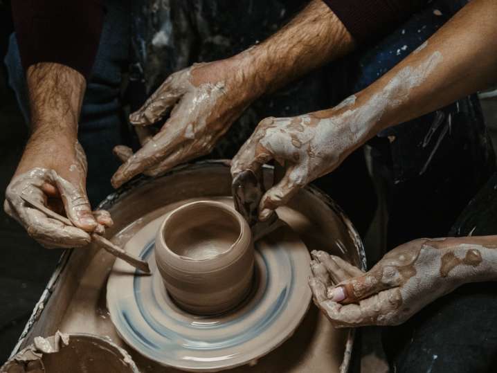 four hands shaping pottery on the wheel Shot