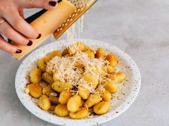 Grating Parmesan over gnocchi Shot