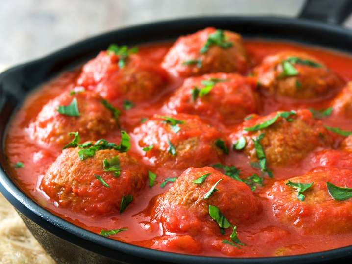 Simmering meatballs in tomato and basil sauce Shot