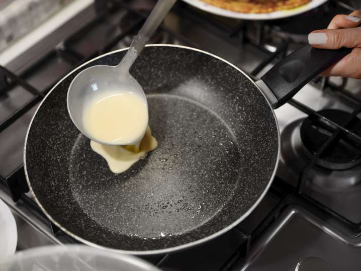 Pouring crepe batter to a hot pan Shot