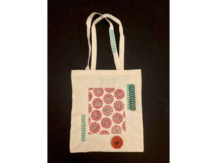 Bay Area - A fabric tote bag with pink floral and leaf block prints, placed near small bottles of paint Shot