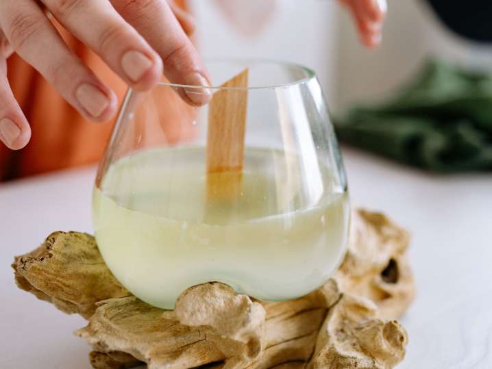 Boston - Close-up of a person inserting a wooden wick into a glass filled with wax Shot