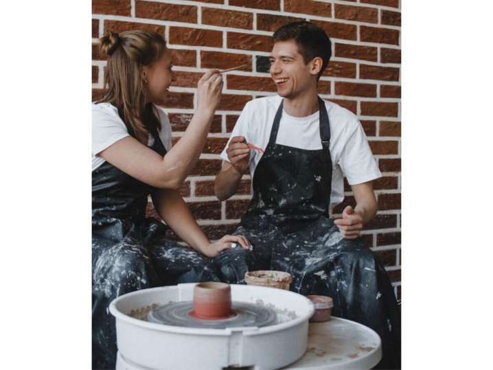 NYC - Playful couple in aprons painting each other’s faces during a pottery wheel session Shot