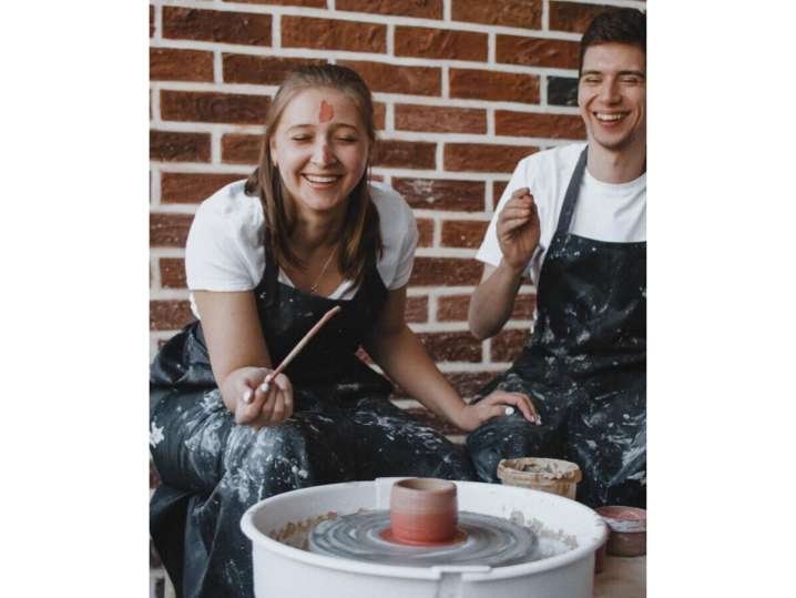 Los Angeles - Couple laughing while working on pottery wheels in a studio with a brick wall background Shot