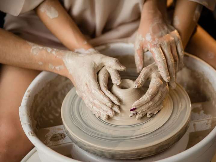 Chicago - Close-up of two pairs of hands shaping clay together on a pottery wheel Shot