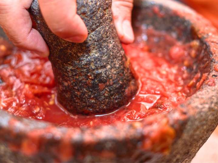 Boston - Hand using a traditional molcajete to grind ingredients for salsa Shot