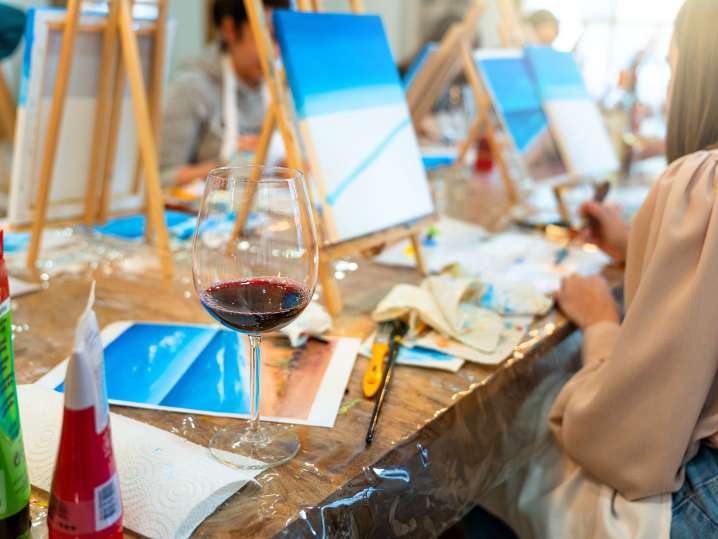 Boston - Paint supplies, wine glasses and canvas setups at a busy paint and sip table Shot