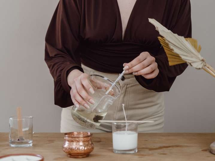 Atlanta - Person pouring wax into a glass jar on a table Shot