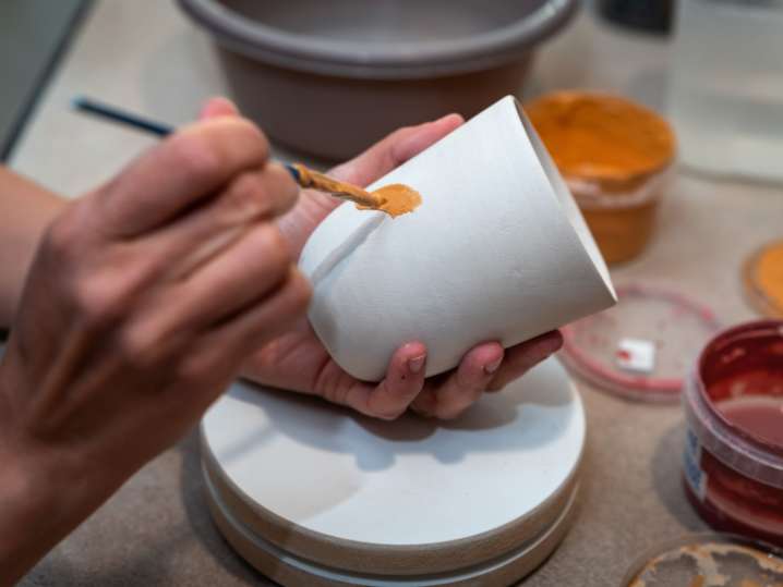 Salt Lake City - Hands painting ceramic bowl with small brush during pottery class Shot