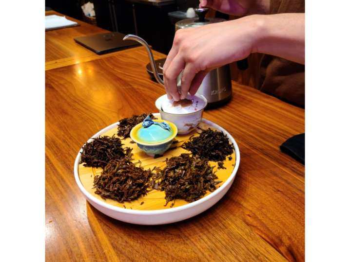 Portland - Close-up of hands pouring hot water over loose-leaf tea arranged on a tasting plate Shot