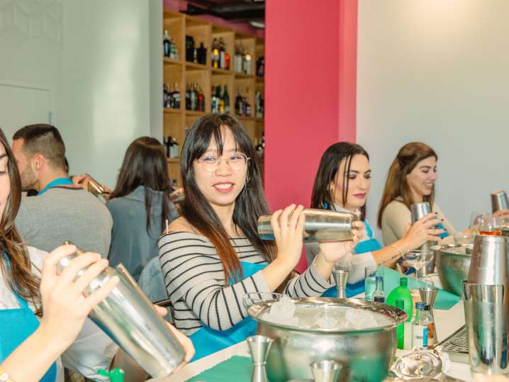 Boston - Participants shake cocktails at a long table during a fun and social mixology class.” Shot