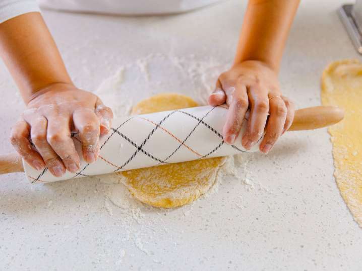 Toronto - Close-up of hands rolling out fresh pasta dough on a floured surface Shot