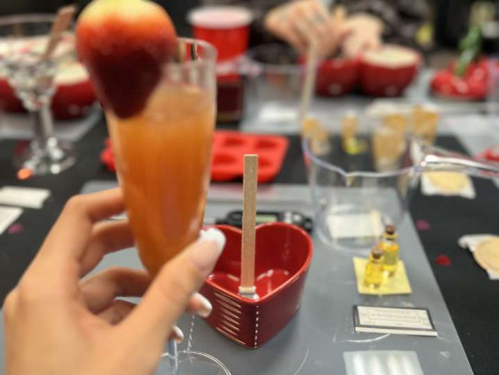 a hand holding cocktail during candle making class Shot