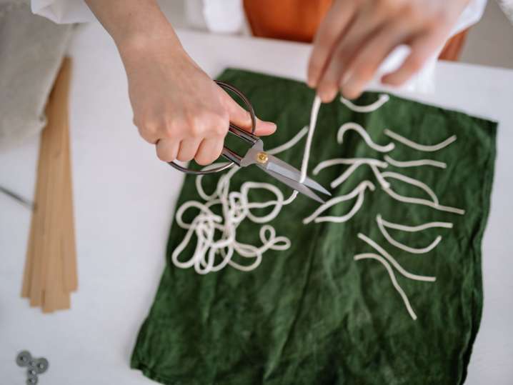 Nashville - Close-up of a person cutting candle wicks placed on a green fabric Shot