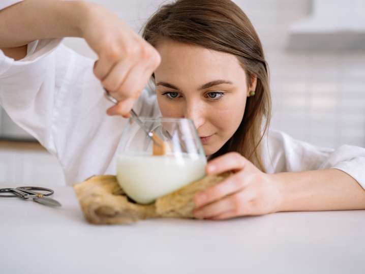 Orlando - A woman focused as she inserts a wooden wick into a candle container during a workshop Shot