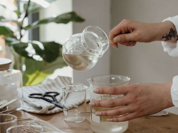San Diego - Hand pouring melted wax into glass jars Shot