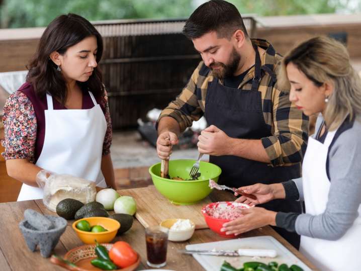 Boston - Group making guacamole together with fresh avocados, tomatoes and other ingredients Shot
