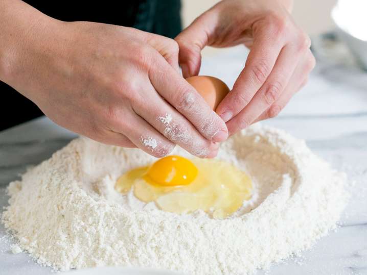 cracking an egg into flour to make homemade pasta dough | Classpop Shot