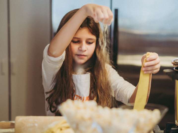 a young girl is adding more flour to her pasta dough | Classpop Shot