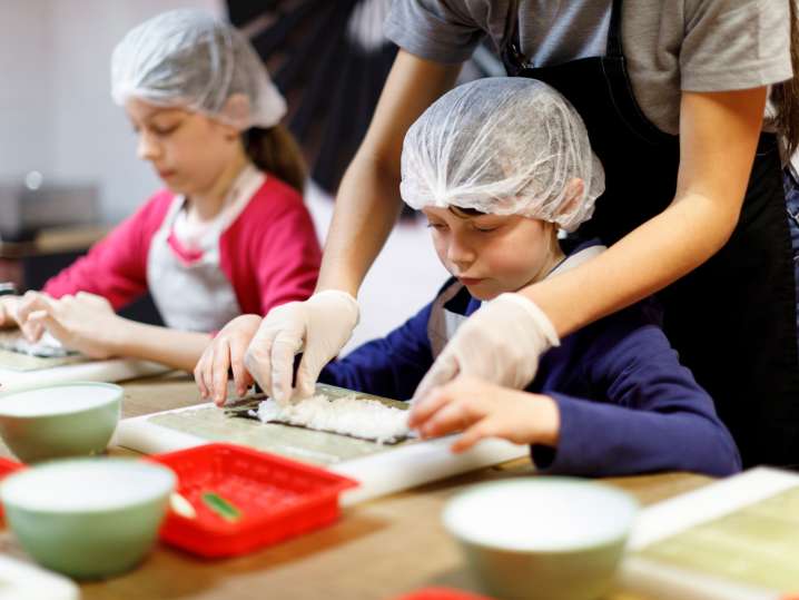 a cooking class teacher is helping kids to roll sushi | Classpop Shot