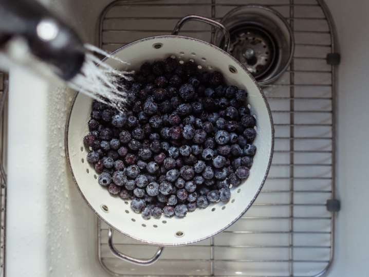 rinsing fresh blueberries in a colander Shot