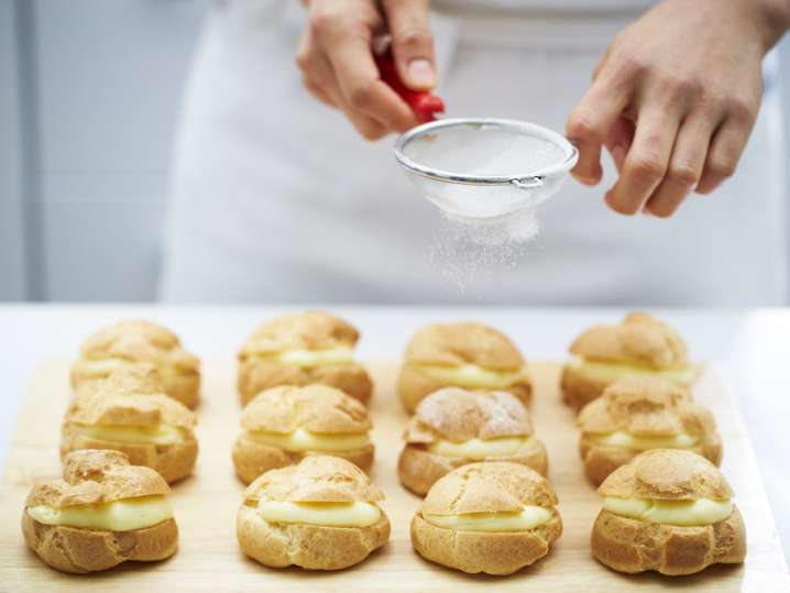 chef dusting powdered sugar over profiteroles Shot