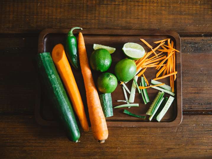 wooden tray with carrots, limes, and cucumber for spring rolls Shot