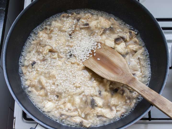 stirring mushroom risotto on the stove with a wooden spoon Shot