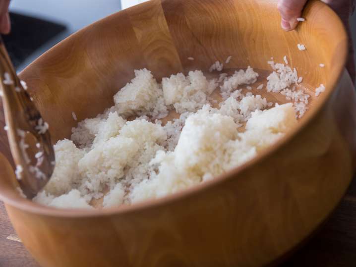 chef stirring sushi rice in a bamboo bowl Shot