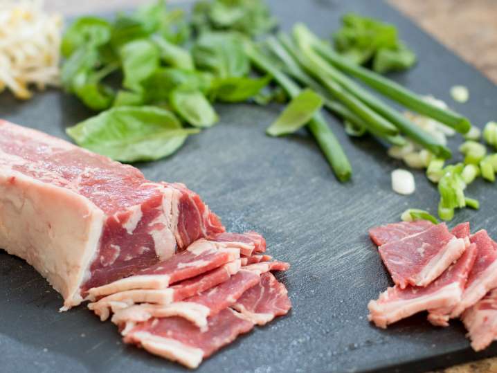 beef, green onion, and herbs on a slate cutting board Shot