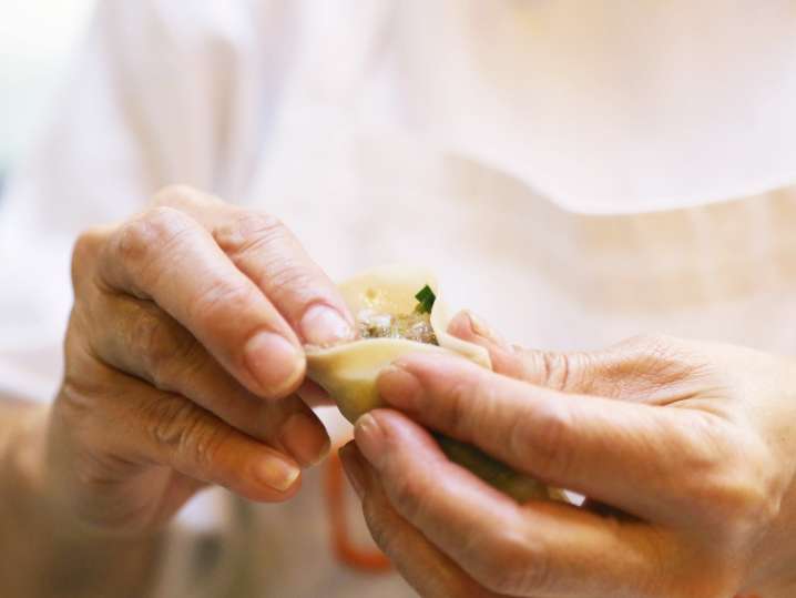 chef filling and folding a wonton wrapper to make gyoza Shot