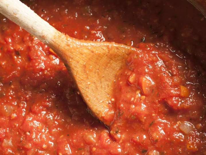 wooden spoon stirring marinara sauce in a pot Shot