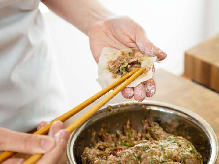 chef filling a wonton wrapper with potsticker ingredients Shot