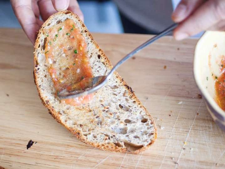 chef spreading tomato dip on toasted bread for pan con tomate | Classpop Shot