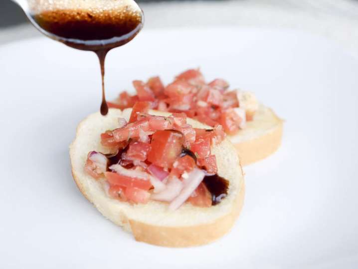 drizzling balsamic vinegar on fresh bruschetta | Classpop Shot