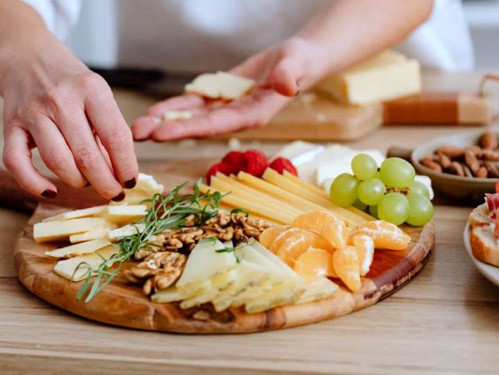 person arranging cheeses on charcuterie board | Classpop Shot