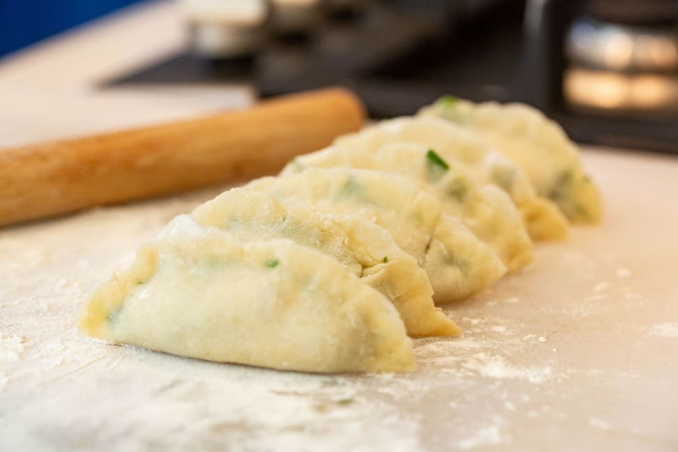 Chicago - Homemade dumplings arranged in a row on a floured countertop next to a rolling pin Shot 1