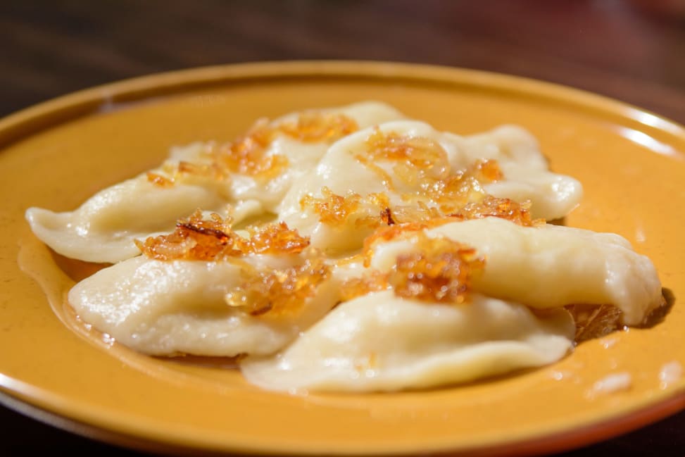 Bay Area - Cooked pierogi topped with butter and caramelized onions on a plate Shot 3