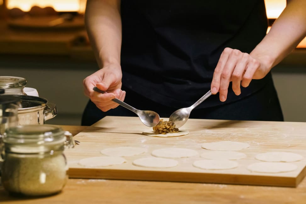 Bay Area - Chef using spoons to portion filling onto rolled pierogi dough circles Shot 2
