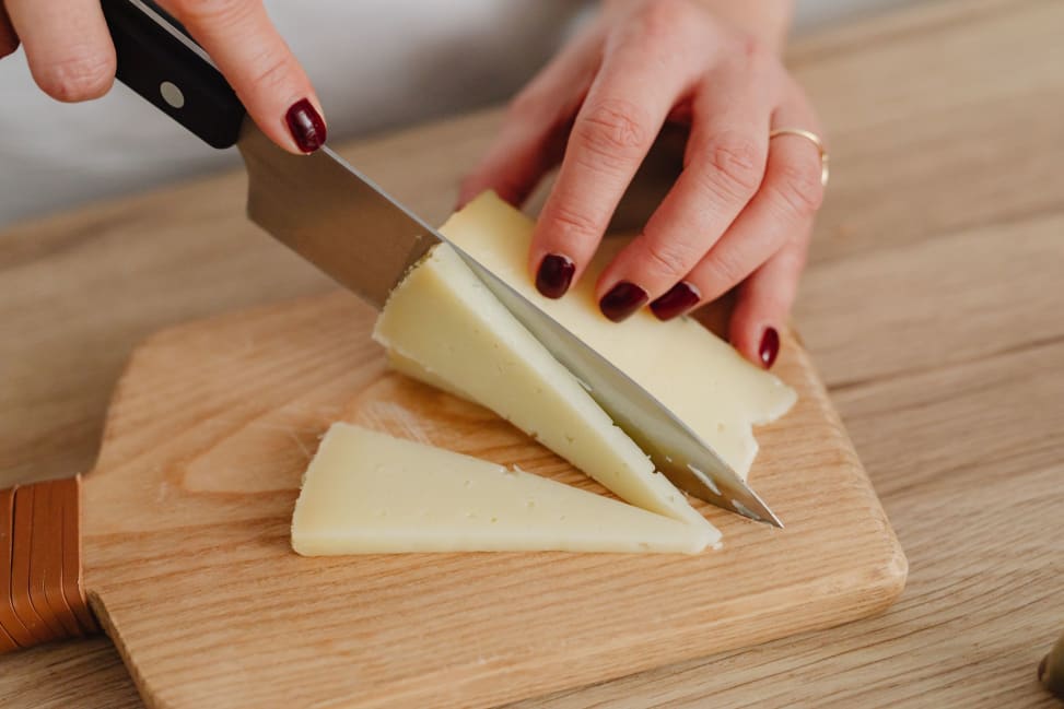 Orlando - Hands of a Person Slicing Cheese on Brown Wooden Chopping Board Shot 2