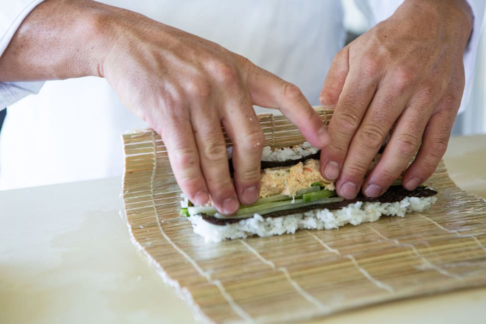 Hands rolling uramaki sushi with a bamboo mat | Classpop Shot 4