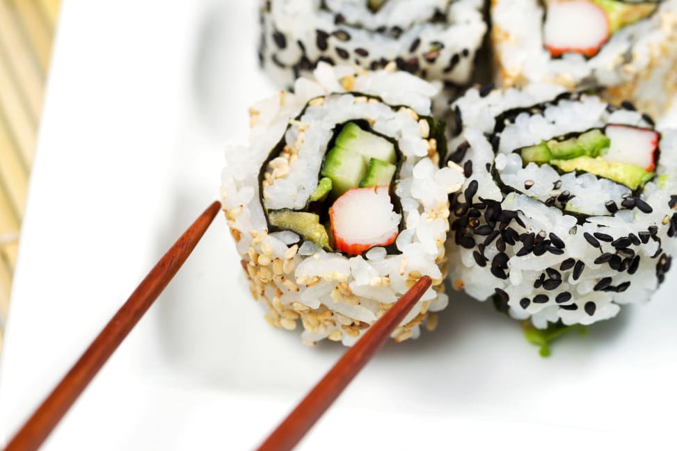 chopsticks picking up a california sushi roll Shot 3