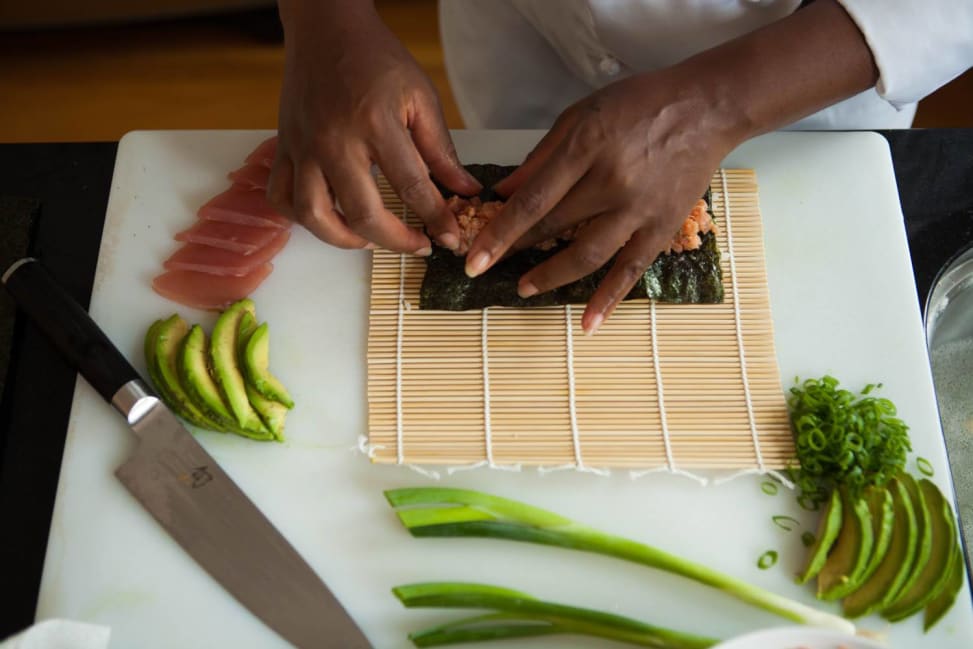 chef's hands preparing a tuna roll on a bamboo mat Shot 2